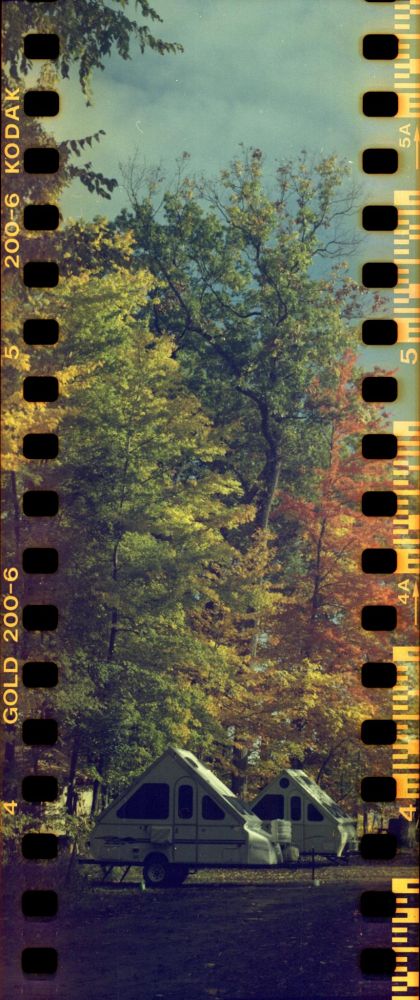 a color photo of two aliners beneath colorful trees adorned with fall foliage. the photo has sprocket holes exposed and is 2.5 tiles taller than it is wide.