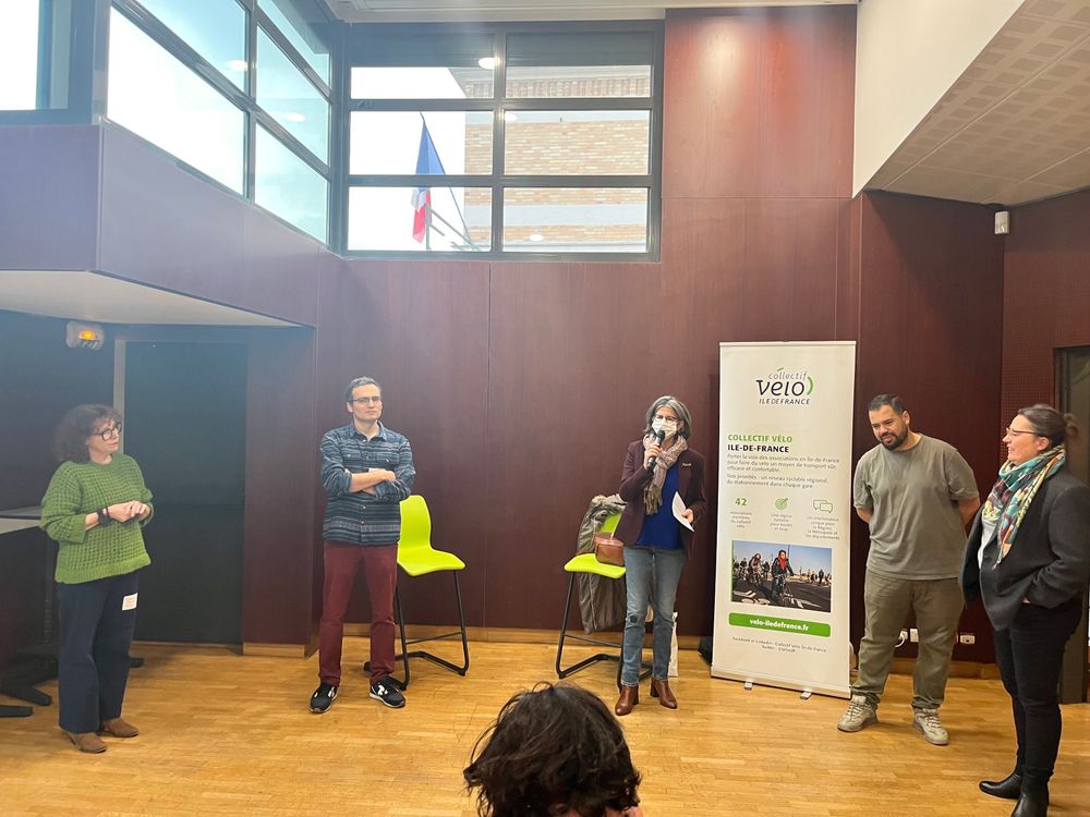5 personnes debout devant une assemblée dans une salle de reunion, la maire tenant le micro