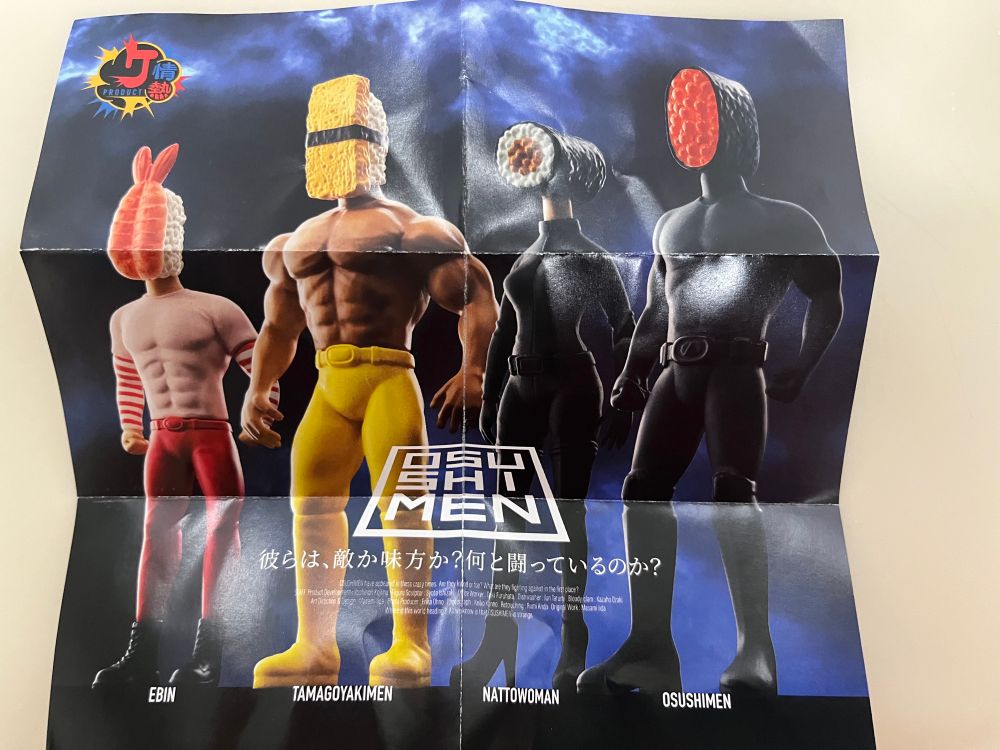 Paper insert with the Osu Shi Men gashapon, human bodied figures with sushi heads. They look like superheroes.
