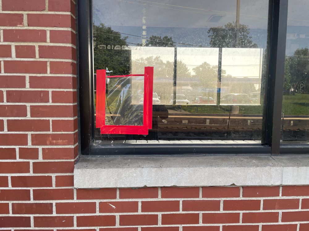 Photo of a square made w red duct tape on a window (close up)