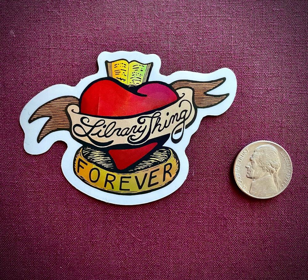 A photograph of a LibraryThing Forever sticker, next to a nickel.