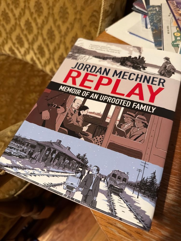 A picture of the English edition of Jordan Mechners graphic novel „Replay“ on a wooden table next to a green chair 