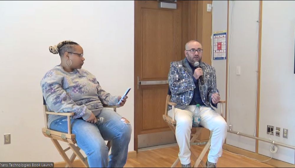 two seated people holding microphones