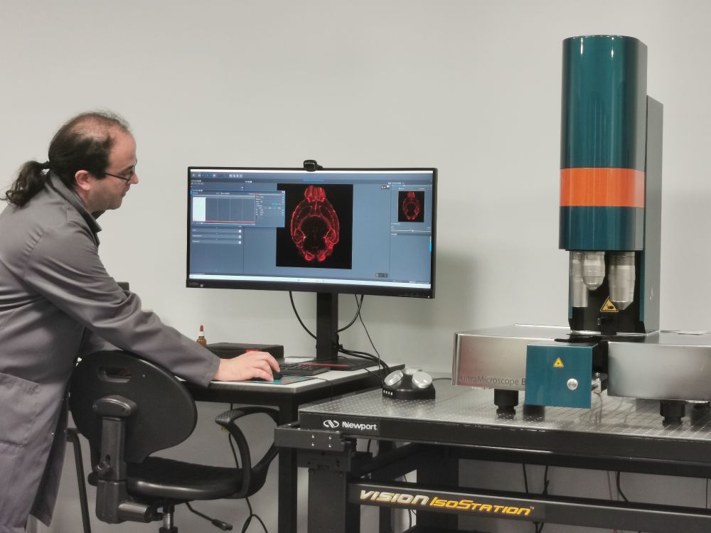 Dr Graham Hickman demonstrating whole brain staining of a mouse brain with a red fluorescent signal, next to the Miltenyi Blaze UltraMicroscope