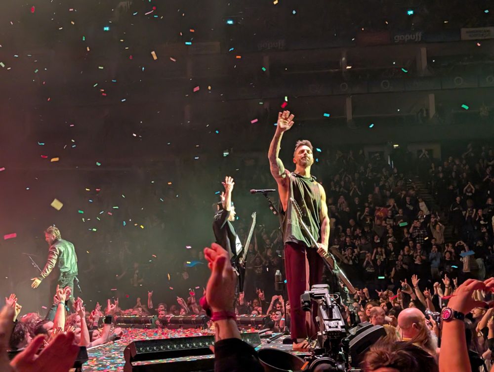Three members of the band Bullet for my Valentine wave to the crowd in thanks after their performance, as confetti falls from above 