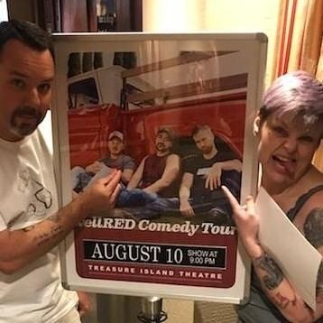 Two humans pose next to sign advertising the WellRed Comedy Tour at Treasure Island Theatre. The poster depicts comedians Corey Forrester, Drew Morgan and Trae Crowder sitting in front of an old red and white pickup truck.