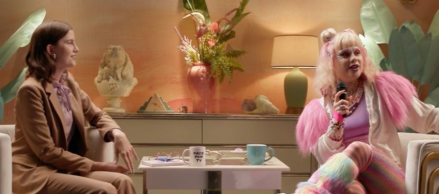 cena de "very important people", uma série de humor independente estadunidense onde vic michaelis, como elu mesme, entrevista um monte de gente estranha e maluca. nessa captura de tela, é a princess emily