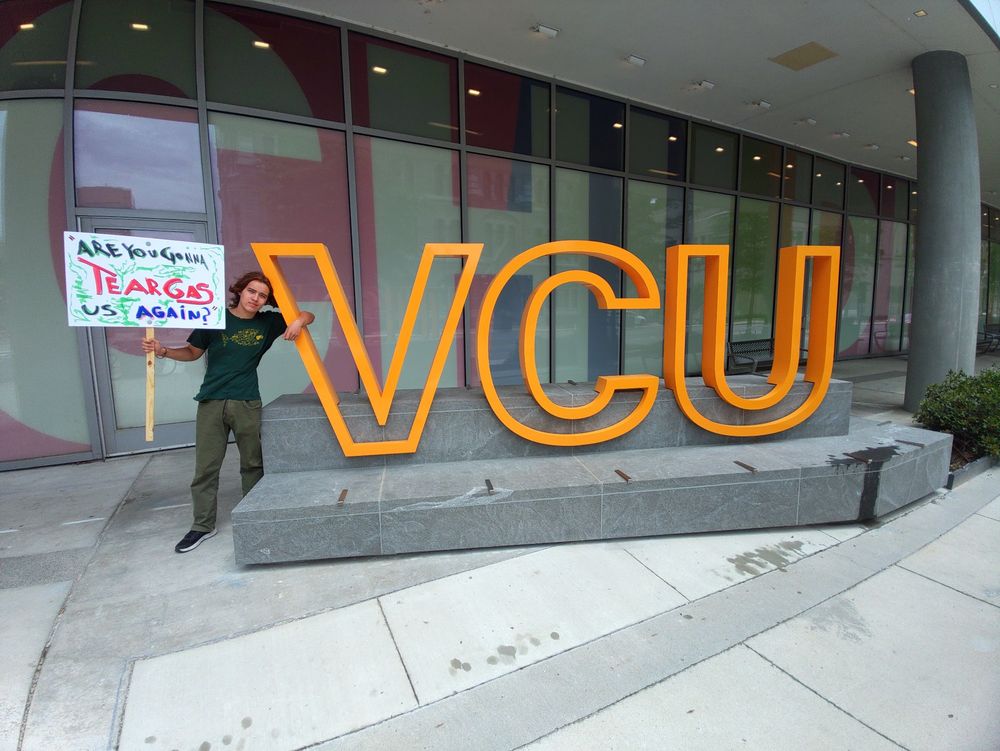 Photo of Oscar Ferguson-Osborne  holding sign reading "are you gonna tear gas us again?" In quotes next to VCU sign in Richmond, Virginia