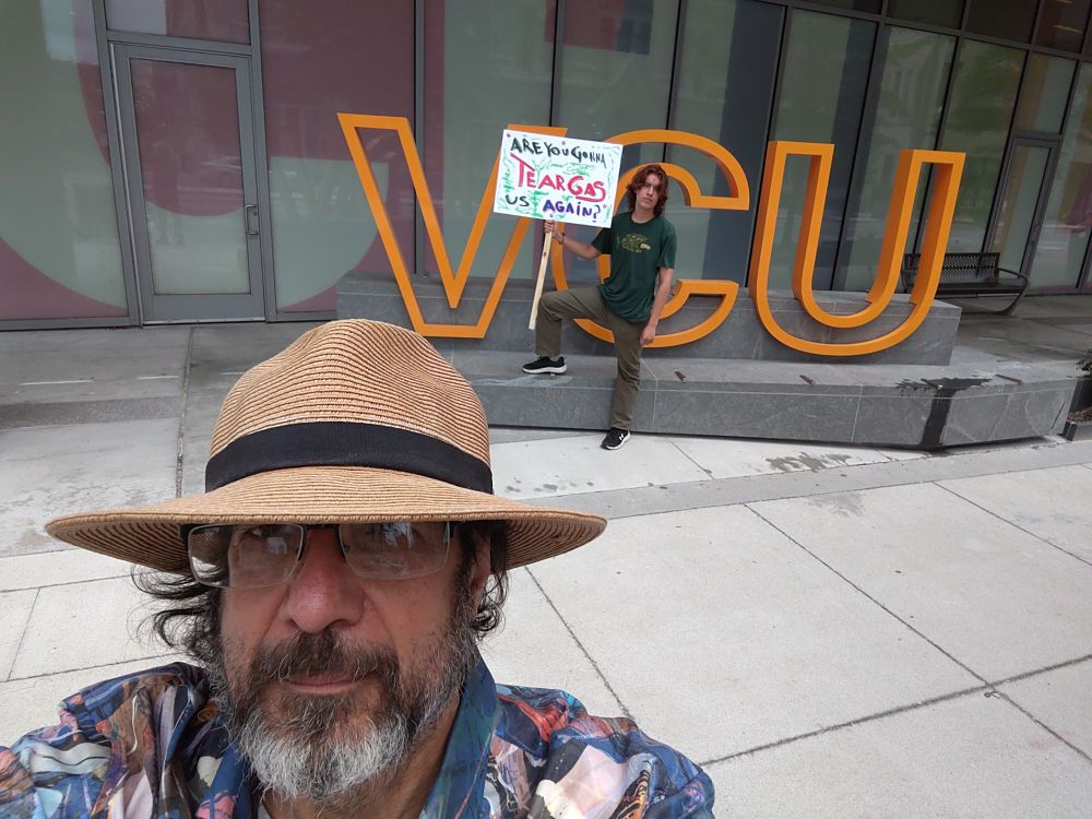 Photo of Arthur Brill and Oscar Ferguson-Osborne  holding sign reading "are you gonna tear gas us again?" In quotes next to VCU sign in Richmond, Virginia