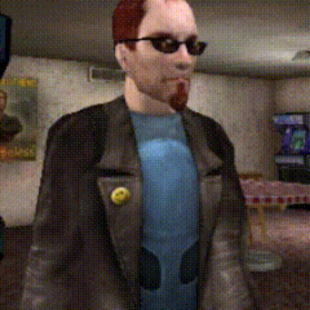 a man wearing sunglasses and a blue shirt with a yellow button on his jacket