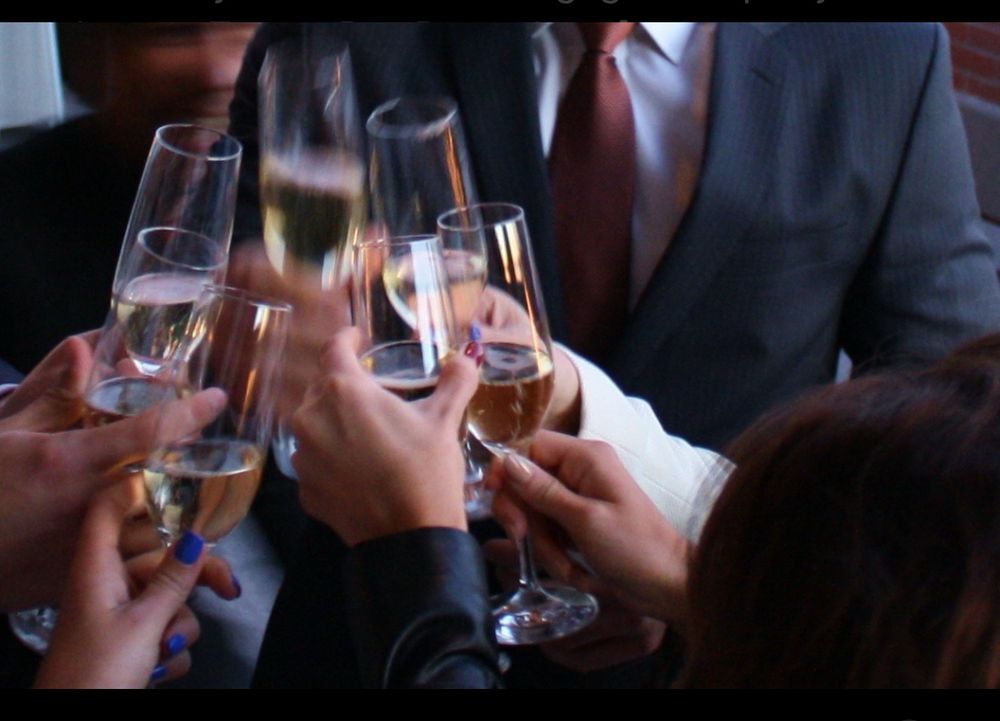 Six upscale peoples hands clanging wine glasses together, half filled with champagne cheering, and engagement. 