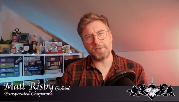 Caucasian Man in red plaid shirt with beard and glasses in front of a book case filled with board games. On screen text read Matt Risby (he/him) Exhausted Chaperone 