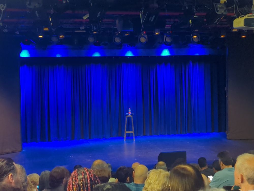 במה מוארת בכחול עם שולחן ועליו בקבוק מים ומיקרופון