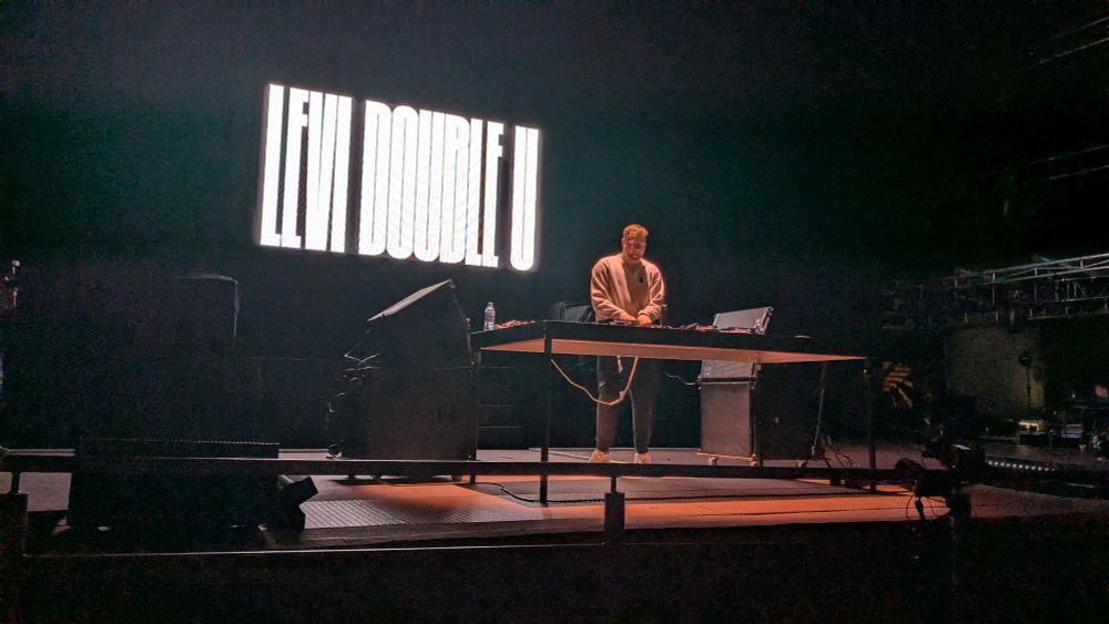 photo of a dj set with "levi double u" in fancy graphic design text on the giant screen behind the dj