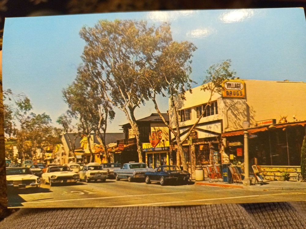 A mid-1970s postcard from Balboa Island, California, featuring a picture of a local street full of vintage cars.
