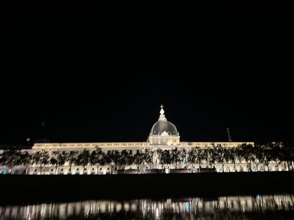 The city hall at night reflected in the river.