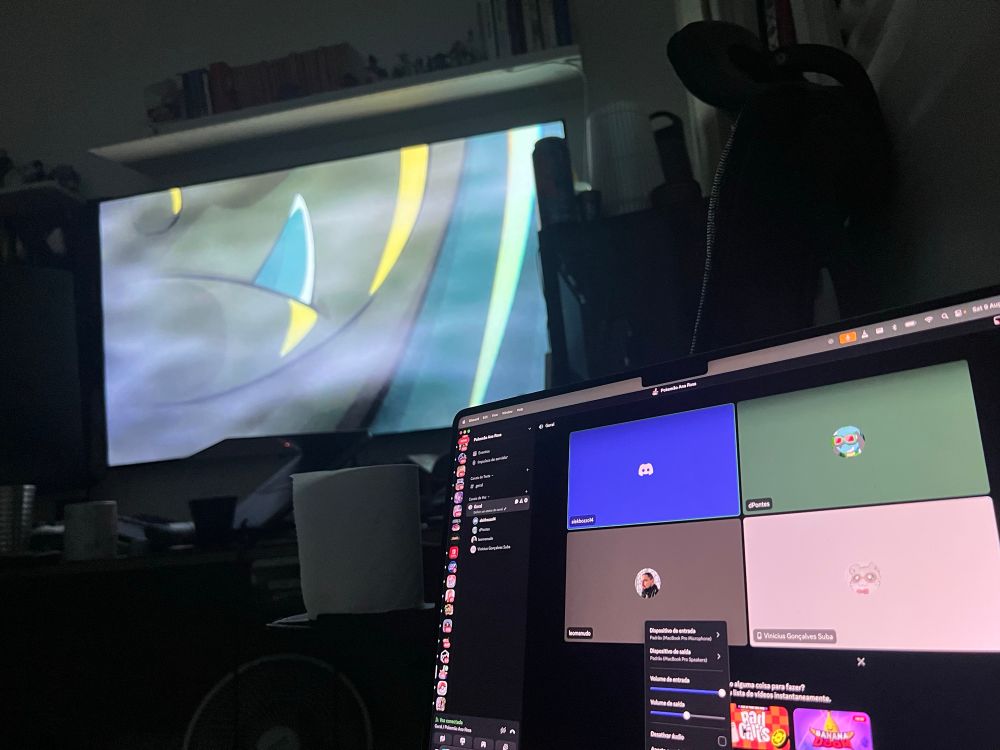 Uma televisão passando one piece no fundo, com um notebook em que sua tela está uma janela do discord.