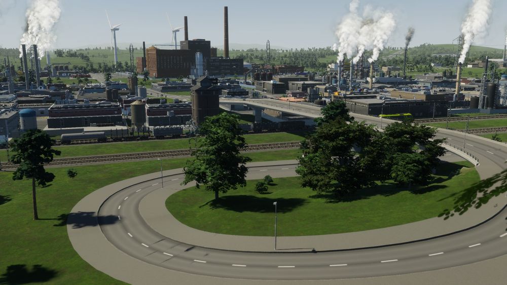 Capture d'écran du jeu Cities: Skylines 2 : La zone industrielle s'étend dans la vallée avec des usines uniques, une gare de fret qu'on devine grâce aux rails, et de l'industrie zonée générique