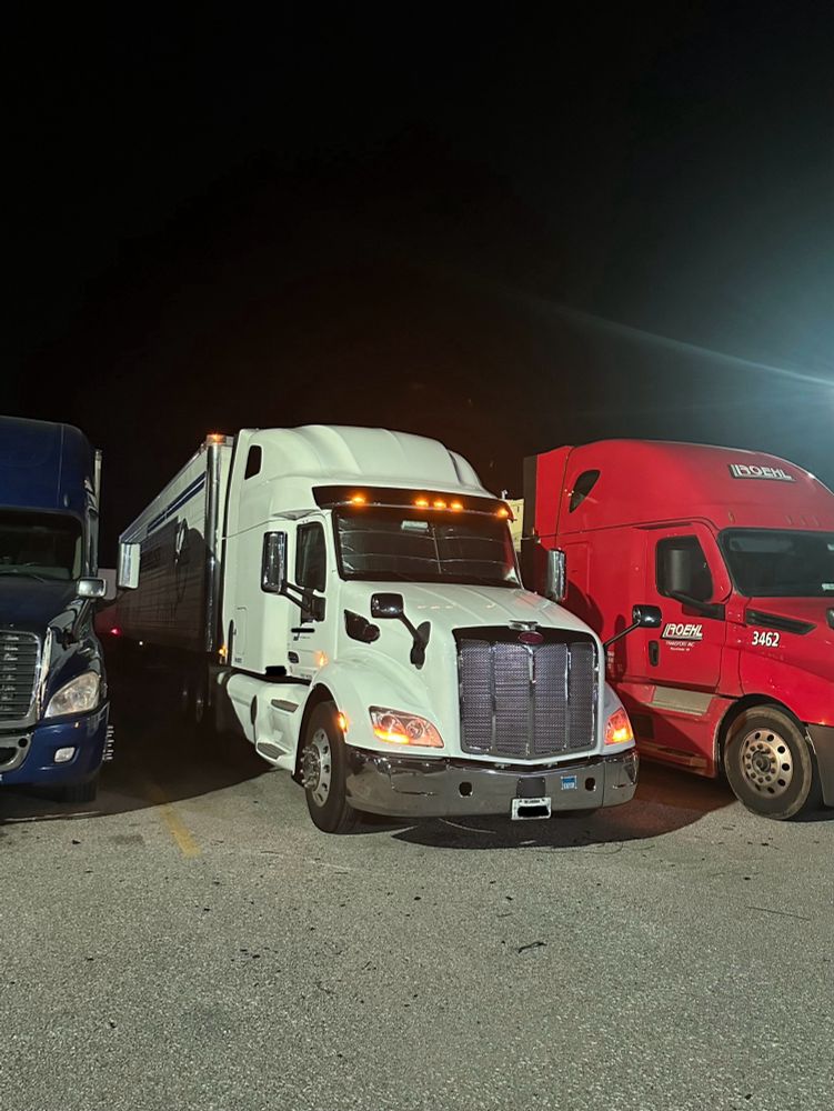 White Peterbilt parked at night with just the amber marker lights on