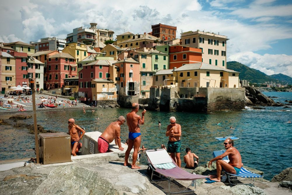 Eldery men in front of Boccadasse village at the Sea in Italy. It is sunny and warm.