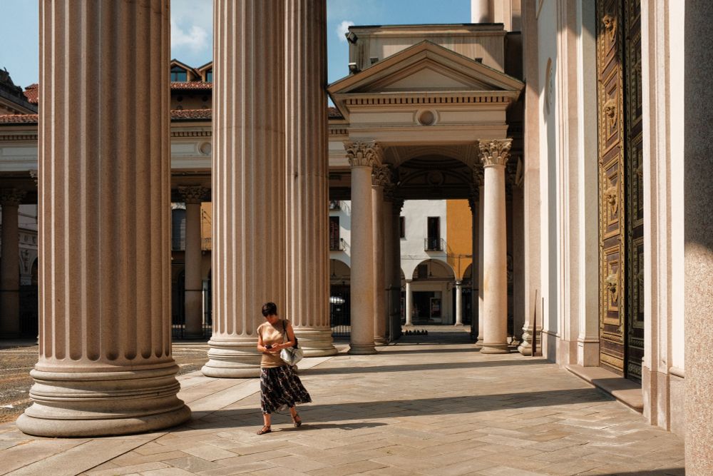 Woman walking near the Cathedral of Novara city in Italy. Sunny and shadows. 