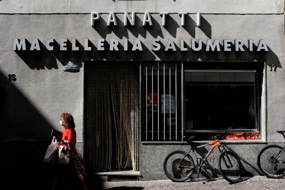 Salumeria in Chiavenna, Italy. A Woman leaves the butcher in a red dres
