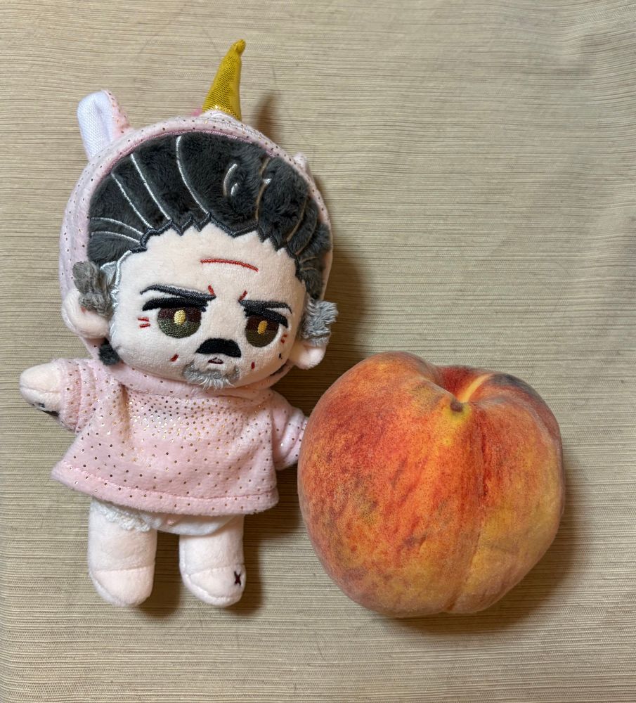 Izzy doll in unicorn onesie pictured with one large peach 