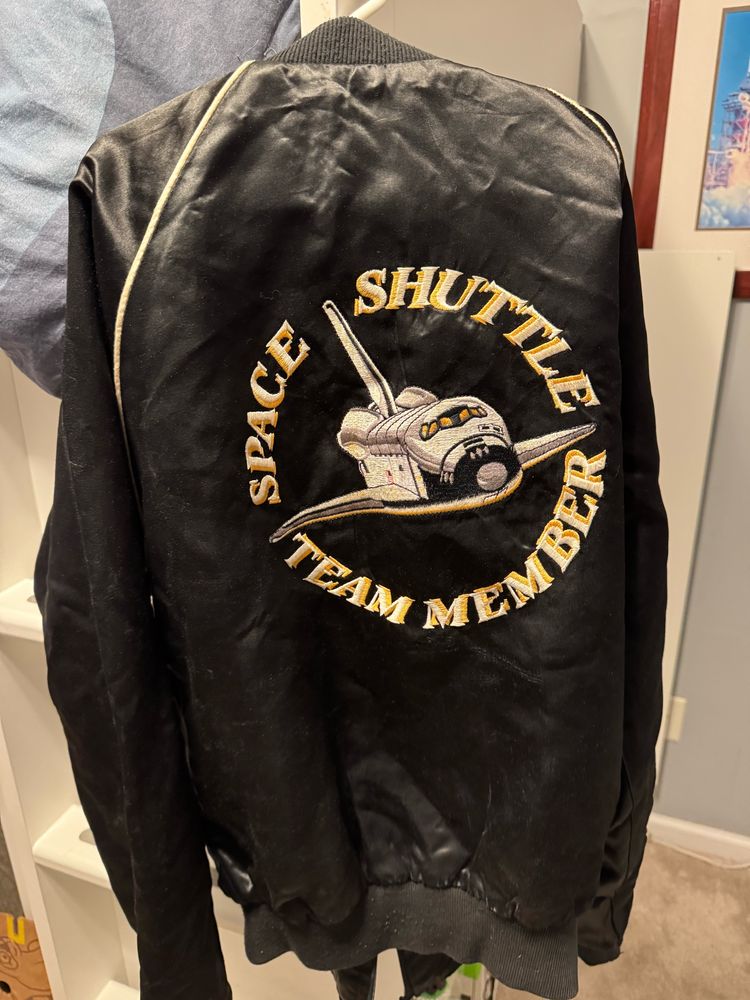 Black jacket with Space Shuttle and circular logo spelling out “Space Shuttle Team Member”