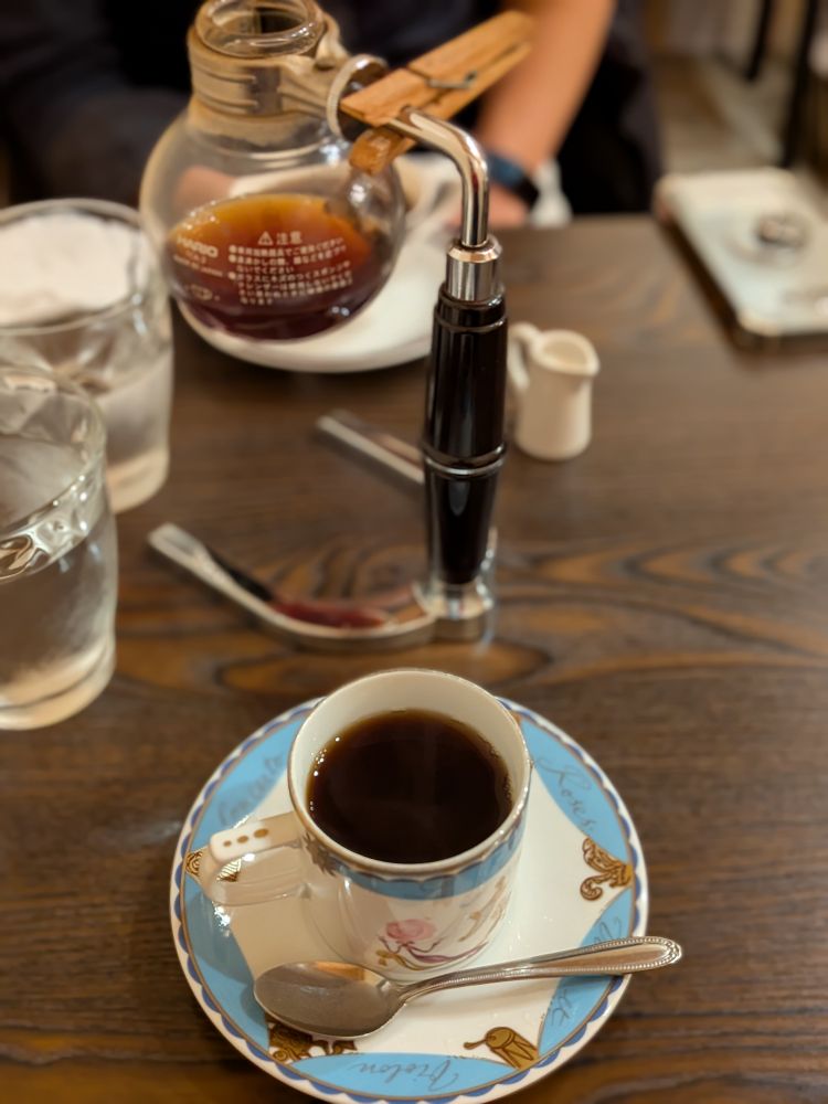 手前にコーヒーカップ、奥におかわりのコーヒーが入ったサイフォン