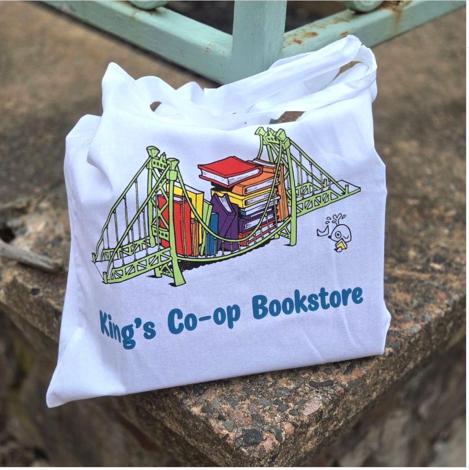 a white cloth bag on a stone block. The bag reads King's Co-op Bookstore and it features a green bridge sagging under the weight of a rainbow of books.
