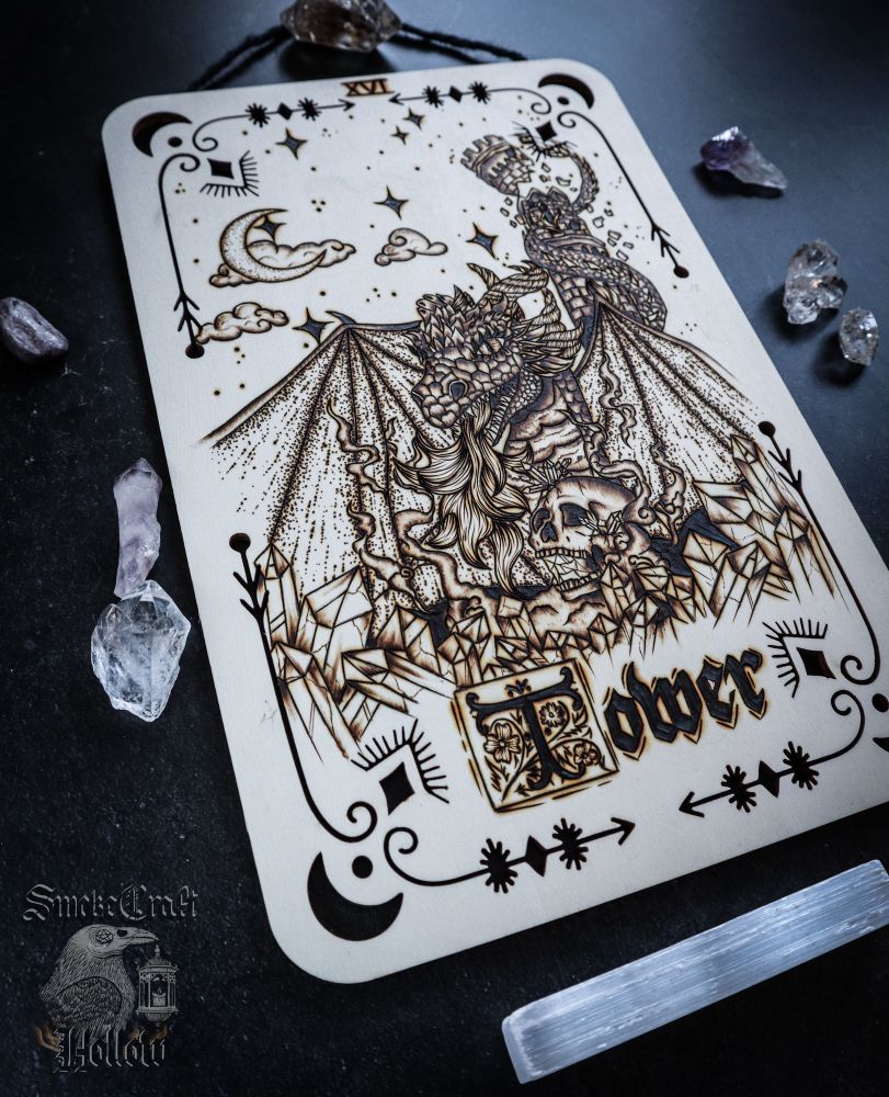 Woodburned tarot card for the tower, depicting a dragon destroying a tower guarding a skull and crystals under a night sky created for the upcoming Smokecraft Tarot 