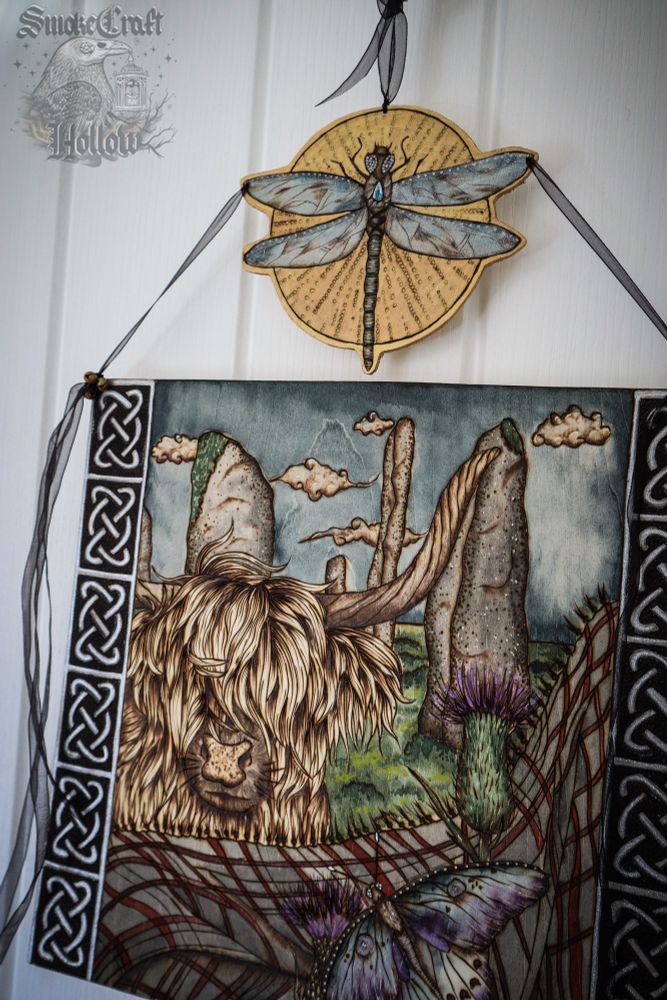 Woodburned highland cow art with dragonfly, Scottish thistle, butterfly and Celtic knots. 