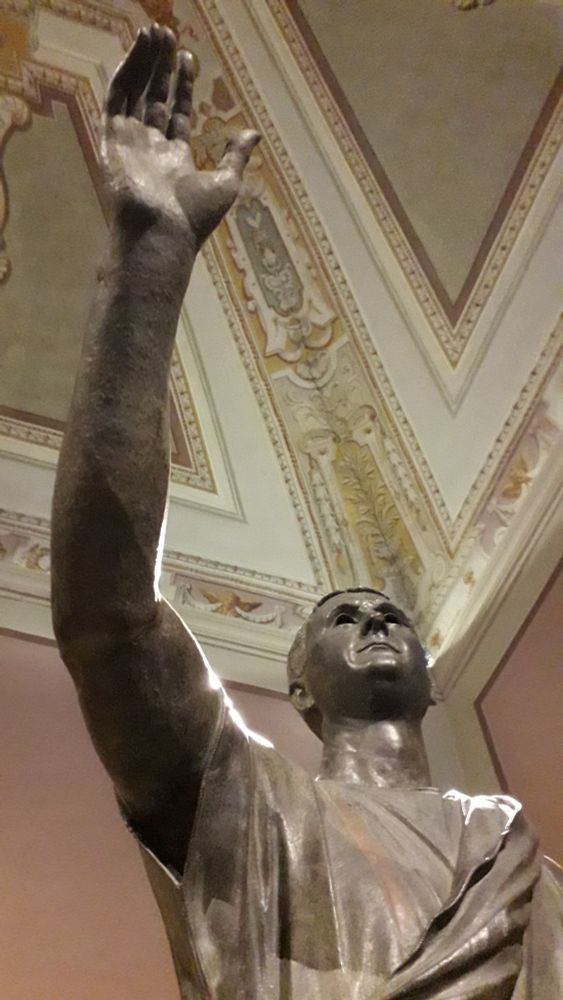 a photo of the Arringatore (also called the Orator), a bronze statue from the end of the 2nd or the beginning of the 1st century BC, depicting a Roman official as a speaker. It can be admired at the Museo Archeologico Nazionale di Firenze.