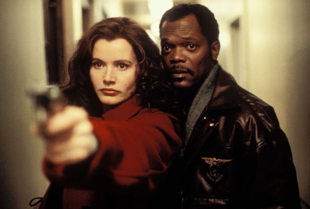 Still from The Long Kiss Goodnight. Samuel L Jackson stands beside Geena Davis as she aims a gun toward the camera.