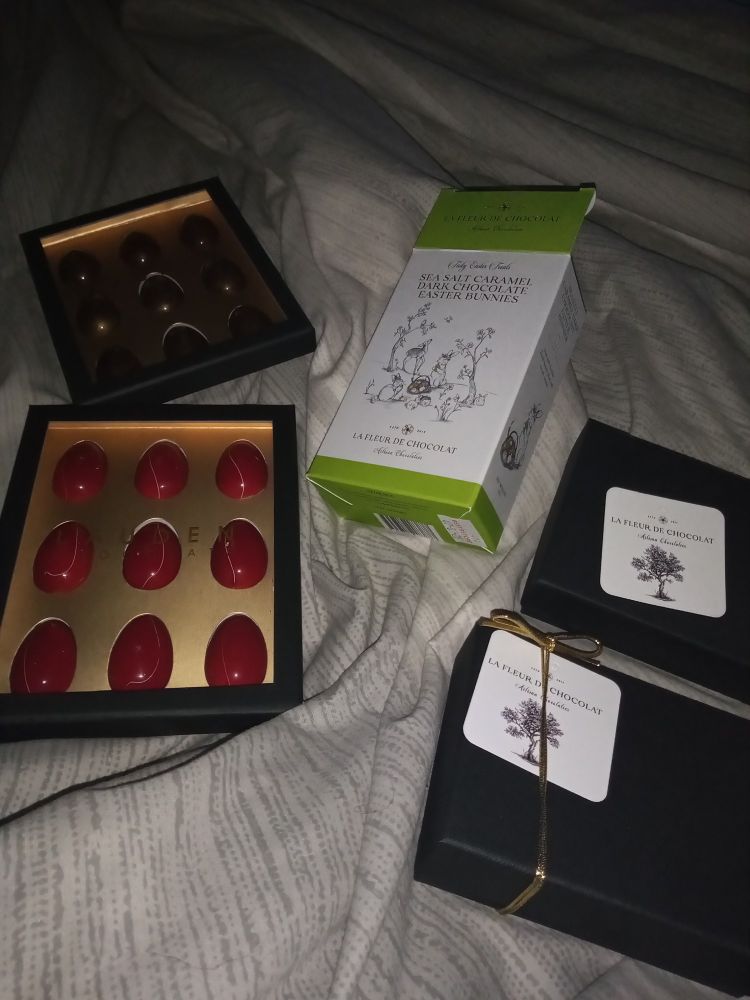 Five boxes of very, verrrry fine Easter chocolates lying on a rumpled bed, with me (not pictured) still in it. Salted caramel and passion fruit eggs; Kalamansi chocolates; apricot and jasmine chocolates; caramel and sea salt Easter bunnies.