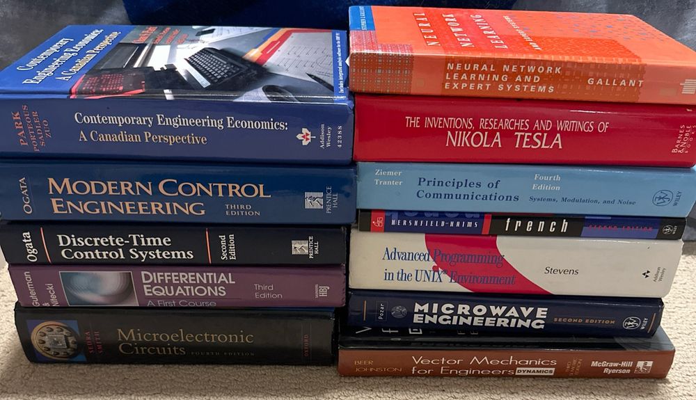 Two stacks of engineering textbooks sitting on a carpeted floor. The orange book is Neural Network Learning and Expert Systems by Stephen I. Gallant, from 1993.