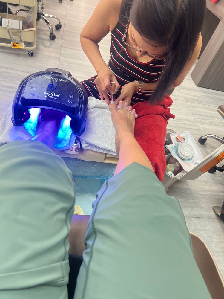 Picture of a feet getting nail Polish and the other under the black light 