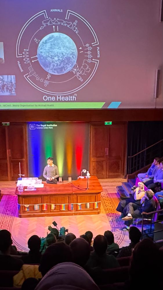 Gabriel Astorga presenting in the RI lecture theatre with a slide that says one health over him