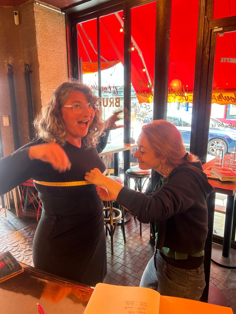 A woman is taking the bust measurement of another woman in a bar
