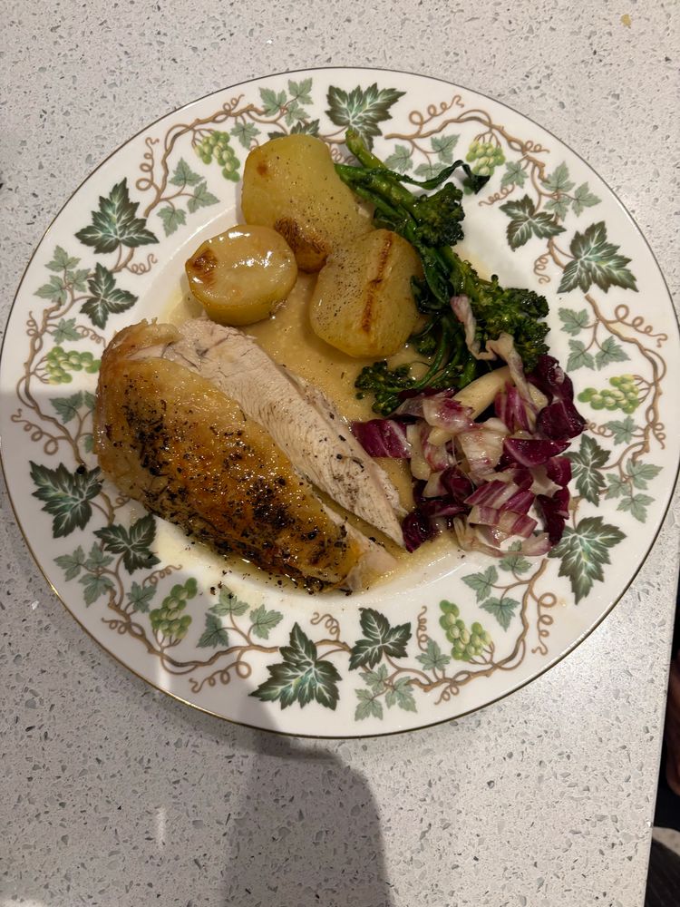 grape leaf pattern plate with a roasted breast of chicken, 3 roasted potatoes, sprigs of broccolini and sliced radicchio and apple salad