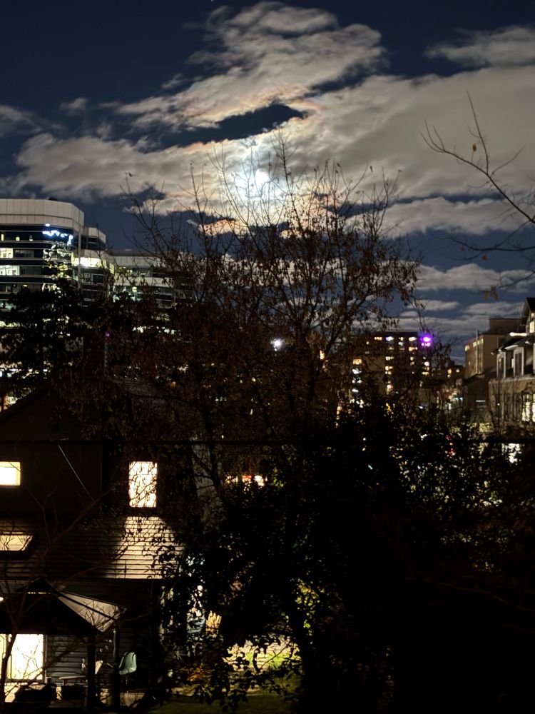 the beaver moon is rising up in the sky in the horizon glowing brightly through the moving clouds