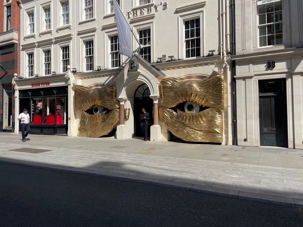 Huge pair of Surrealist gold eyes outside a shop.
