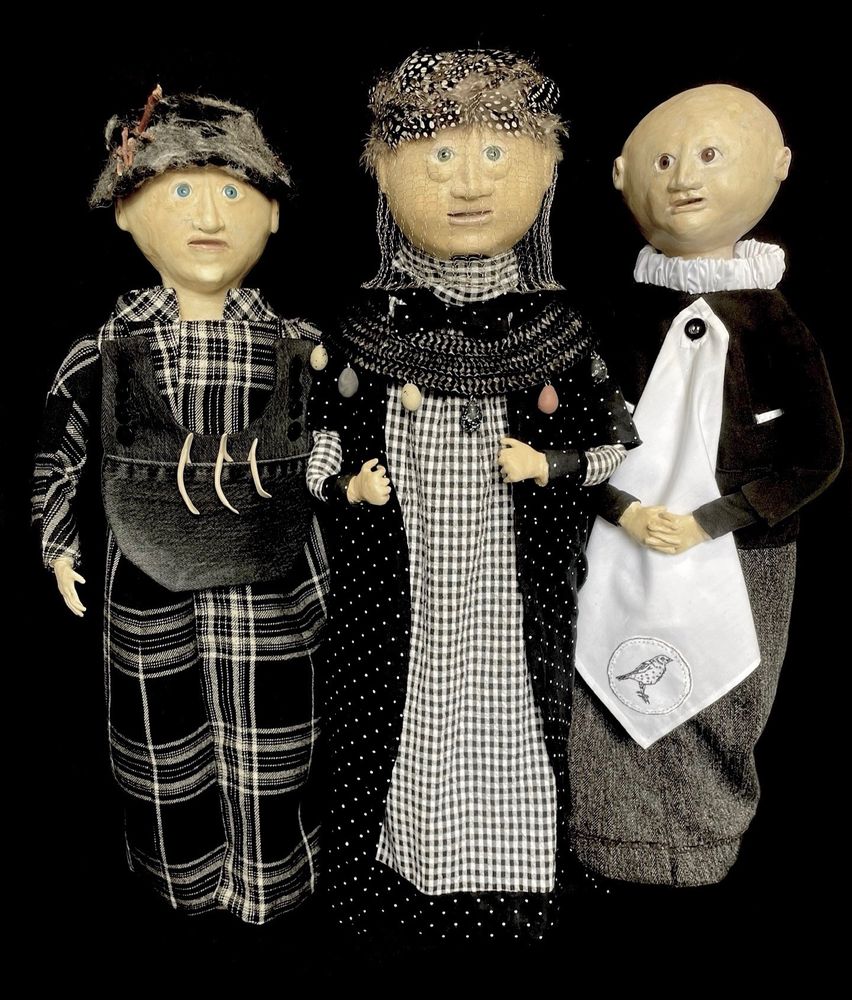 Three fabricated figures, dressed in black and white and showing references to things collected from birds, such as eggs and feathers.