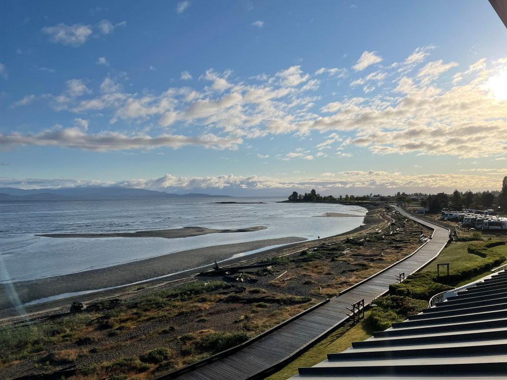 Long uninhabited boardwalk along the ocean front in Parksville Bc. Tide is out revealing sandy tidal flats. Sunny day.