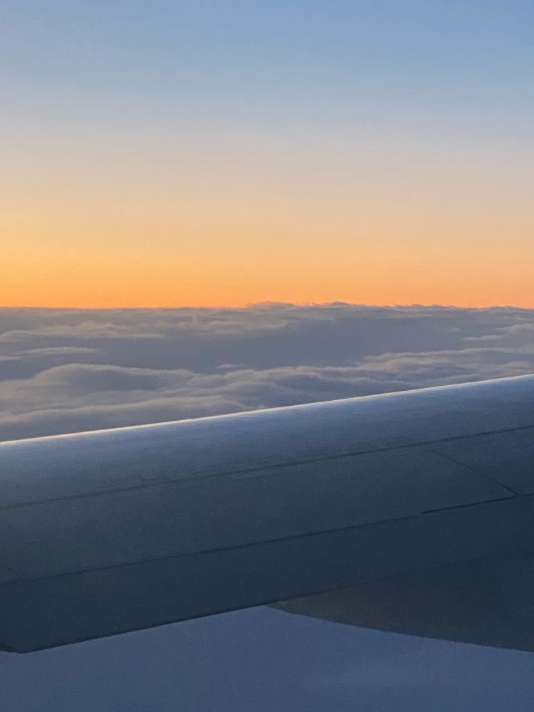 a photograph out an airplane of a sunrise from above the clouds 