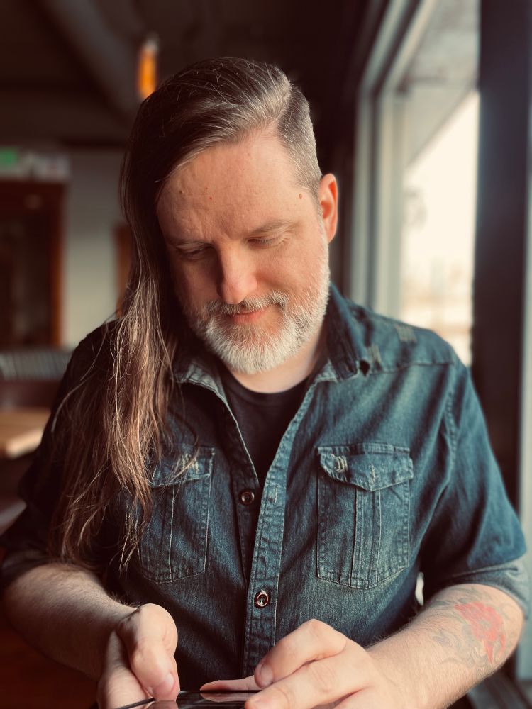 More info in first image. Robert smiling bashfully, eyes cast down to his phone. 