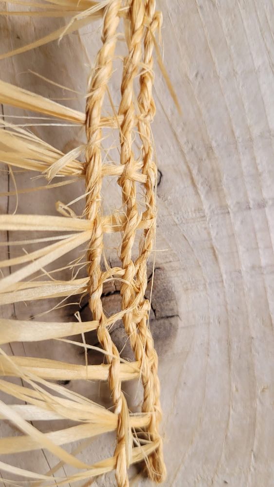 Close-up of a first attempt at Twining. Pale yellow strips of plant fibre (lime bast) are twisted into cord, with cross-threads to form a net-like structure.