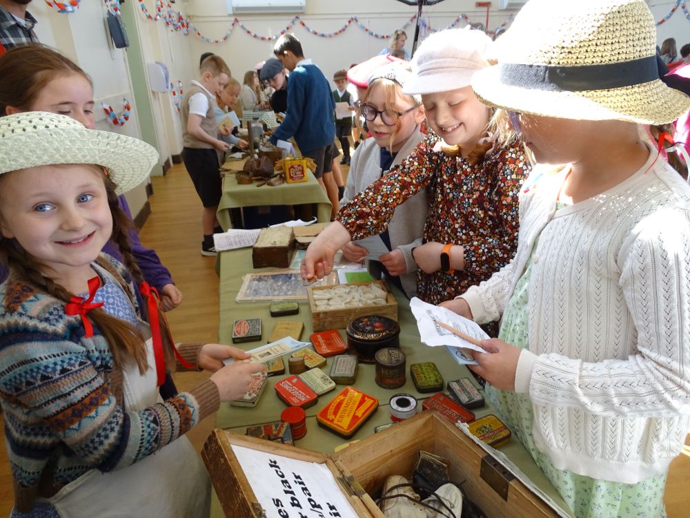A group of girls shopping at the General Store. The table has items from 1940s & the girls have pre-decimal money.