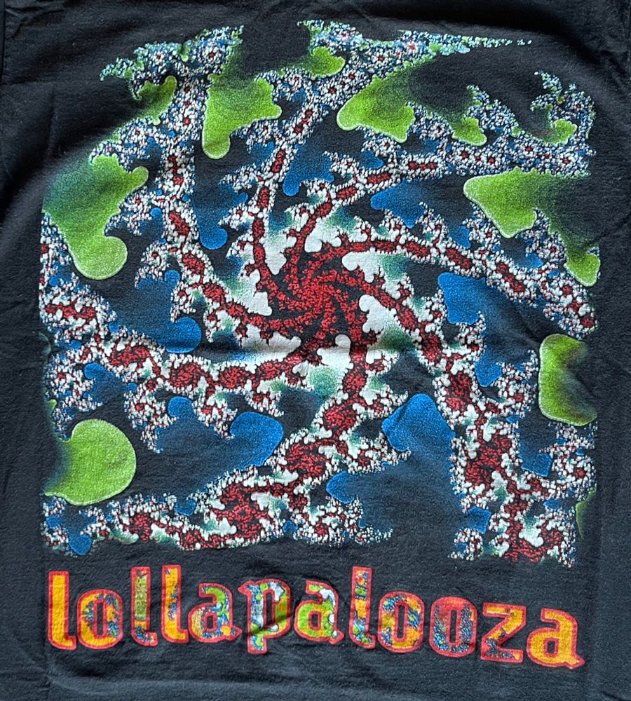 A close-up of a black t-shirt with red, green, blue, and white spiral design and “Lollapalooza” underneath
