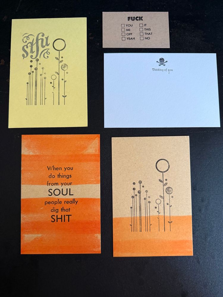 Picture of four notecard and one business card sized prints against a black backdrop. 